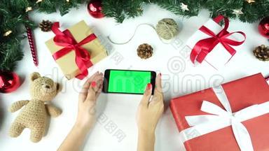 木制背景。 上景。 黑色智能手机，绿色屏幕躺在桌子上，上面假日装饰。